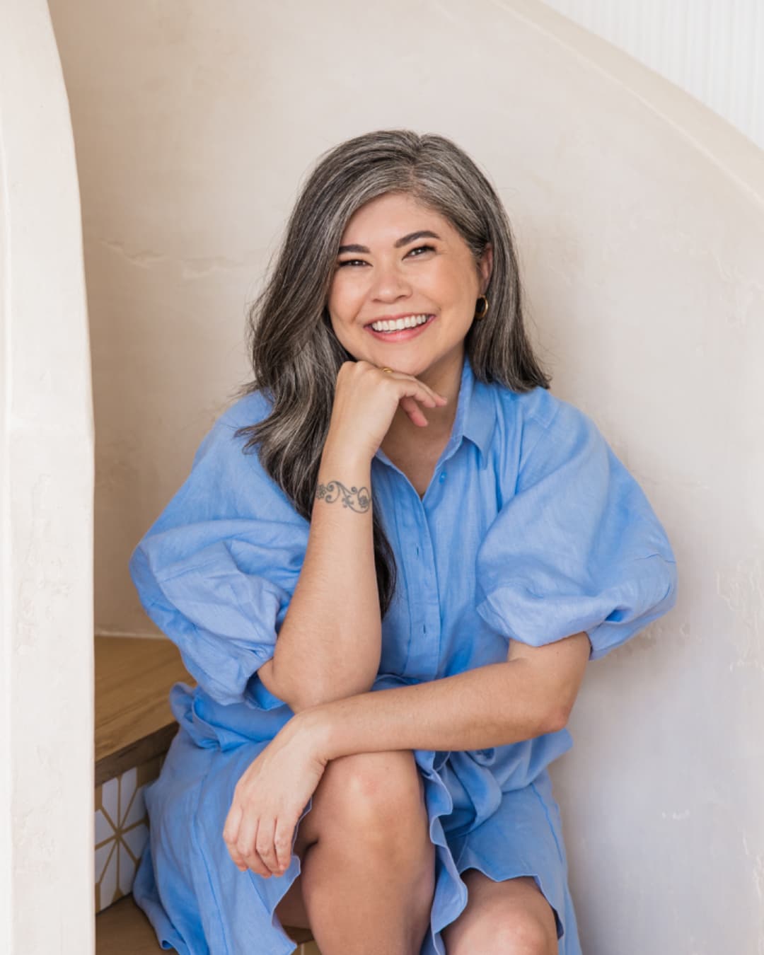 Jennifer Burger from Simply + Fiercely sitting on stairs and smiling at the camera 